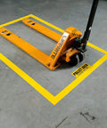 Heavy Duty Polyester Floor Marking Tape In Bright Yellow With Kick Ass Adhesion For Concrete Warehouses And 2 Inch By 100 Foot Roll marking a pallet jack spot on a warehouse floor.