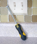 Carbide Tip Grout Removal Hand Tool With Soft Grip Reversible Triangle Blade leaning on countertop in front of tile wall.