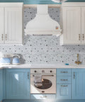 Modern kitchen with Penny Round Tile Peel And Stick Backsplash Kit With White Marble Look And Silver Metal Accent Self Adhesive Mosaic Tiles behind oven and cabinets.