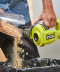 Person pouring wood shavings from clear container into trash with Compact 18V Lithium Ion Handheld Vacuum With Beast Mode Suction Power.