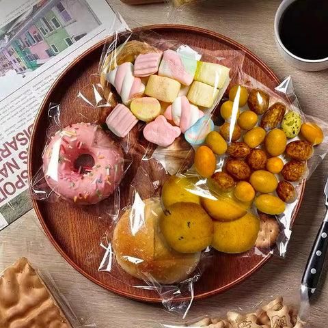 Clear 4x4 Inch Resealable Cookie Bags filled with cookies, candy, and treats on a wooden platter