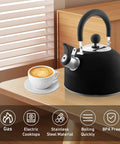 2 Quart Stainless Steel Whistling Tea Kettle For Stovetop No Fuss Quick Boil With Spill Proof Lid Works On Gas Electric Glass And Induction Ideal For Home Dorm Apartment Black on kitchen countertop next to cup of coffee.