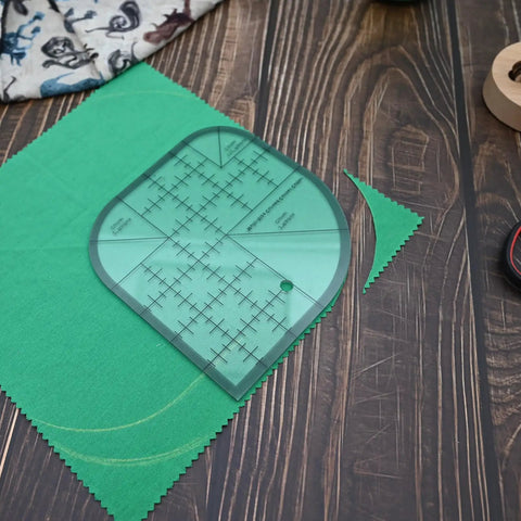 Clear Acrylic Quilting Ruler With Templates And Curved Corner Cutter For Precise Fabric Cutting placed on green fabric.