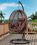 Egg Chair With Stand For Indoor And Outdoor Relaxation on a patio, featuring a brown wicker frame and plush cushioning.