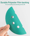 Close-up of a hand holding a 5-Inch 8-Hole Wet Dry Sanding Discs 1000 Grit Polyester Film Backed Heavy-Duty Hook And Loop Sandpaper