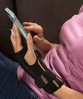 Unisex Fingerless Wrist Wrap With Ice Pack And Heat Therapy worn during smartphone use for pain relief, black, adjustable support.