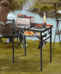 Small Folding Grill Table For Outdoors With Three Adjustable Heights Lightweight Portable Aluminum Camp Table For Camping Picnics BBQ Black 24 By 16 Inches set up by a river.