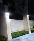 1100 Lumen Solar Outdoor LED Flood Light With PIR Motion Sensor Black illuminating garden wall at night