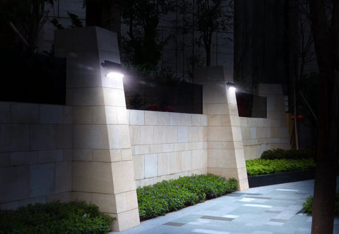 1100 Lumen Solar Outdoor LED Flood Light With PIR Motion Sensor Black illuminating garden wall at night