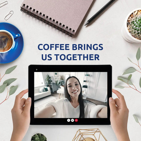 Person video calling on tablet near coffee cup, notebook, and plant with text 'Coffee Brings Us Together'