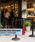 Beefy Two Pack Stanchion Belt Barriers with 11 Foot Black Belts and 40 Inch Posts set up outside a café for crowd control