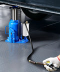 Air hydraulic bottle jack, 32-ton, blue with hand pump and coiled hose under a car.
