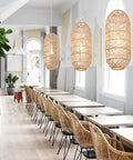 Three Boho Chic Natural Rattan Pendant Lights with Woven Shades hanging in a dining area, showcasing rustic modern chandeliers.
