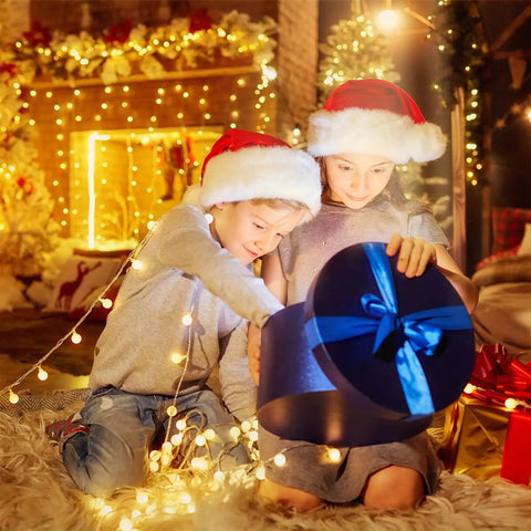 Children in Santa hats opening gift box with Battery Operated Globe String Lights 33ft With 100 LED Globes Remote Control 8 Modes And Timer