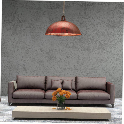 Red industrial-style pendant light hanging over a brown sofa with flowers on the coffee table, featuring rough textured walls.