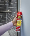 Flex Caulk white 9 oz sealant tube held in hand near a glass shower door for sealing joints