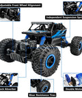 One Eighteen Scale Rock Crawler Remote Control Car With Four Wheel Drive And Two Point Four GHz Off Road Monster Truck Dual Battery Setup Blue Finish For Rugged Trails Pebbles And Dirt, showcasing adjustable front wheel alignment, independent suspension, and shock absorbers.
