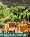 Black waterproof heavy duty silicone coated polyester tarp for awnings, 10x10 feet, in use over outdoor dining area with greenery.