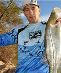 Angler holding a large fish using 12 Piece Spinnerbait Fishing Lure Kit For Bass, Trout, Salmon, Walleye And More by a riverbank.