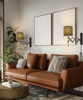 Plug In LED Wall Sconce Set Of 2 In Dark Grey illuminating a modern living room above a brown leather sofa.
