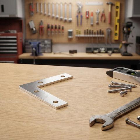 L Shape Metal Corner Brackets 100 Pcs 2.17 By 2.17 Inch Silver Iron Frame Supports on a workbench with tools in background