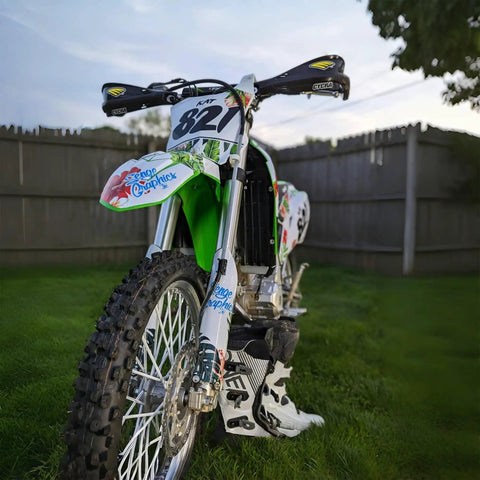 Green motocross bike with Universal Spoke Covers For 8 To 21 Inch Rims With 72 Pcs White Spoke Wraps, parked on grass