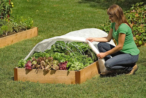 Woman assembling Set Of 6 Garden Hoops Grow Tunnel Supports For DIY Low Tunnel Greenhouse Arch Frame over raised bed