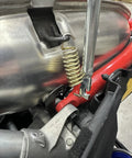 Exhaust spring removal tool installed on snowmobile exhaust; 19-inch metal tool with coil spring and red bracket.
