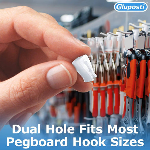 Hand holding clear pegboard clip in front of red-handled tools on a retail display. Clear Pegboard Clips For 1/4 Peg Hooks And Slatwall No Fuss Inventory Clips Peg Locks For Retail Hooks On Peg Board And Slat Wall Panels Ideal For Store Displays 100 Pack.