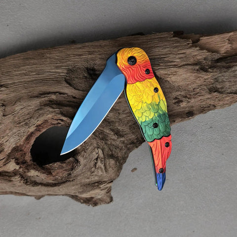 Colorful Parrot Pattern Folding Pocket Knife With Gradient Parrot-Scale Handle, 3-Inch Blue Coated Blade on wood surface.