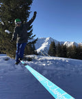 Person balancing on 60ft Slackline Kit Complete Set With Ratchet, Training Line, Bark Protectors, snow-covered mountains in the background