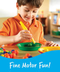 Child using jumbo tweezers for fine motor play with colorful sensory bin tools, Montessori grabber for hands-on learning