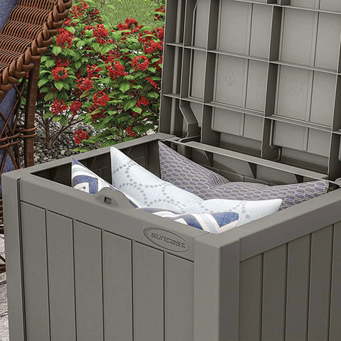 Open 22 Gallon Outdoor Storage Box With Seat In Stone Gray Resin, showing interior with cushions, in garden setting.