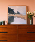 Painting of coastal landscape on dresser with vases and flowers
