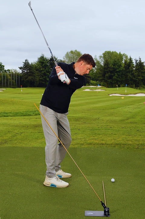 Golfer using Pro Grade Golf Swing Trainer Plate With 2 Premium Gold Alignment Rods, Swing Analyzer Aid on green field