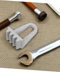 Front view of a silver engine flywheel lock assembly with a U-shaped body on a textured beige mat