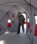 Person inside Quickfish Six Person Portable Pop Up Ice Fishing Shelter With Fully Quilted Insulation No Trip Door And Deluxe Anchors For Hell Of A Winter Setup In Red Black.