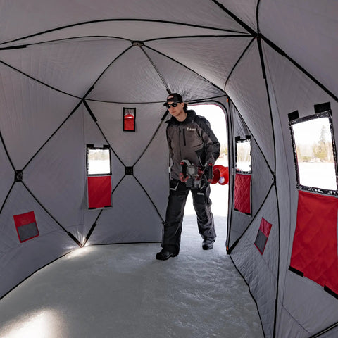 Person inside Quickfish Six Person Portable Pop Up Ice Fishing Shelter With Fully Quilted Insulation No Trip Door And Deluxe Anchors For Hell Of A Winter Setup In Red Black.