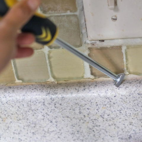 Carbide Tip Grout Removal Hand Tool With Soft Grip Reversible Triangle Blade For Detail Work In Tight Spots Great For Grout Mortar Caulking Residue Cleanup And Precision Scraping being used on kitchen tiles