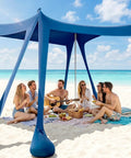 Group enjoying picnic under Spacious 10x10 Beach Tent With UPF 50 Sun Shelter Windproof Frame on sunny beach