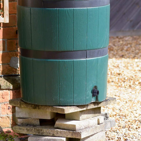 Green rain barrel with a Three Quarters Inch PVC Bulkhead Fitting With Four Millimeter Silicone Seal Gasket for leak-proof water connection.
