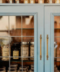 Close-up of a blue cabinet with 10 Pack 3 Inch Hole Centers Antique Brass Cabinet Pulls Vintage Brass Cabinet Hardware in a kitchen setting.