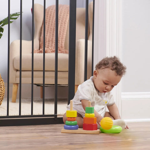 Child plays near Extra Wide Baby Gate For Doorways And Stairs, 30 To 41.5 Inches, Pressure Mounted Wood Gate With Door, One Hand Open.