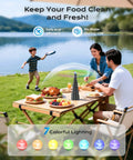 Family dining outdoors with Tabletop Fly Fans With USB Type C Rechargeable Battery And Colorful LED Light Show on a picnic table.