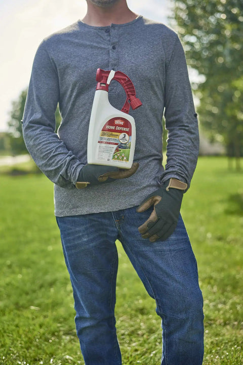 Person holding Ready To Spray Outdoor Insect Killer With Hose End Sprayer For Lawn And Landscape in a garden setting.