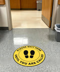 10 Pack Please Wait Here Until You Are Called Sign 12 Inch Square Vinyl Floor Sign in yellow on hospital waiting room floor