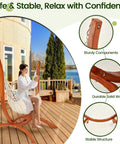 Premium Wooden Hammock Stand for Indoor and Outdoor Use, Heavy Duty Solid Wood Frame Supports Up to 500 Lbs, Weather Resistant with Sun Protection, Safe and Stable Design, Hammock Not Included. Female seated, near house and lake.