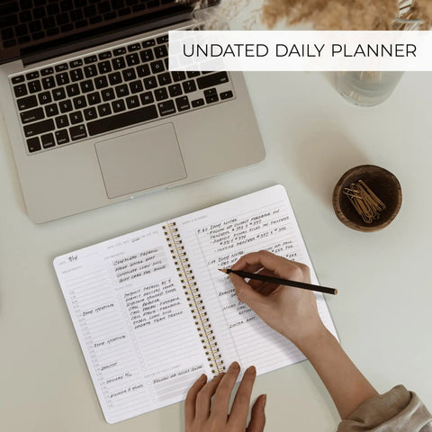 Daily Planner With Hourly Schedule Spiral Notepad For Easy Tasking And Appointment Organization on desk beside laptop and paperclips.