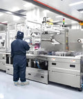 Technician operating automated manufacturing equipment in a cleanroom facility.