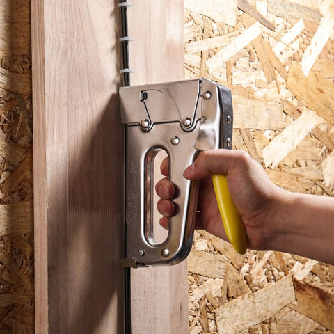 Heavy Duty Staple Gun With Rear Load Magazine For Voice And Data Cables And Wiring in use against a wood panel